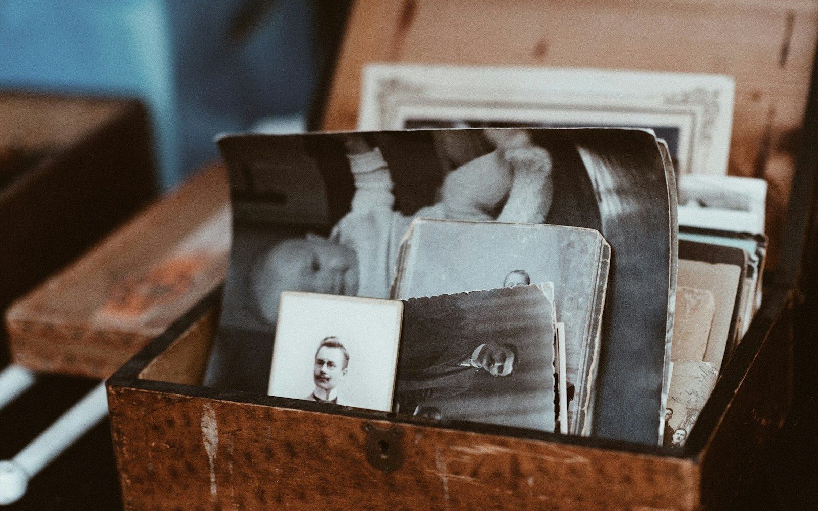 Old sepia family photographs in a wooden keepsake box, representing tracing Colombian ancestry for a citizenship by descent claim