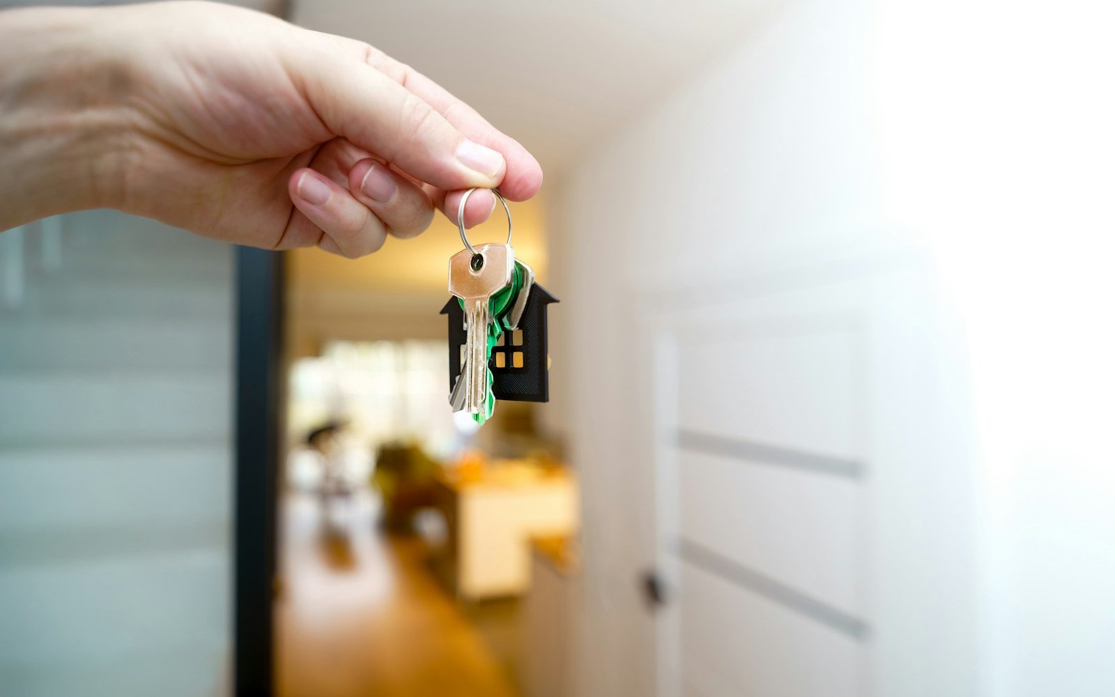 Hand holding a set of house keys inside an apartment doorway, representing landlord-tenant disputes in Colombia