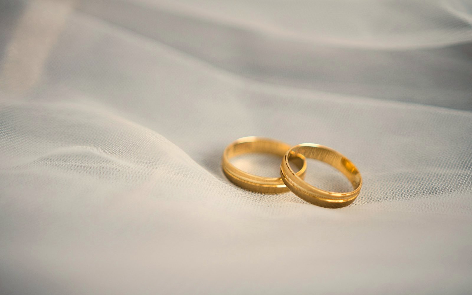 Two gold wedding rings resting side by side on white fabric, representing separating finances during marriage in Colombia